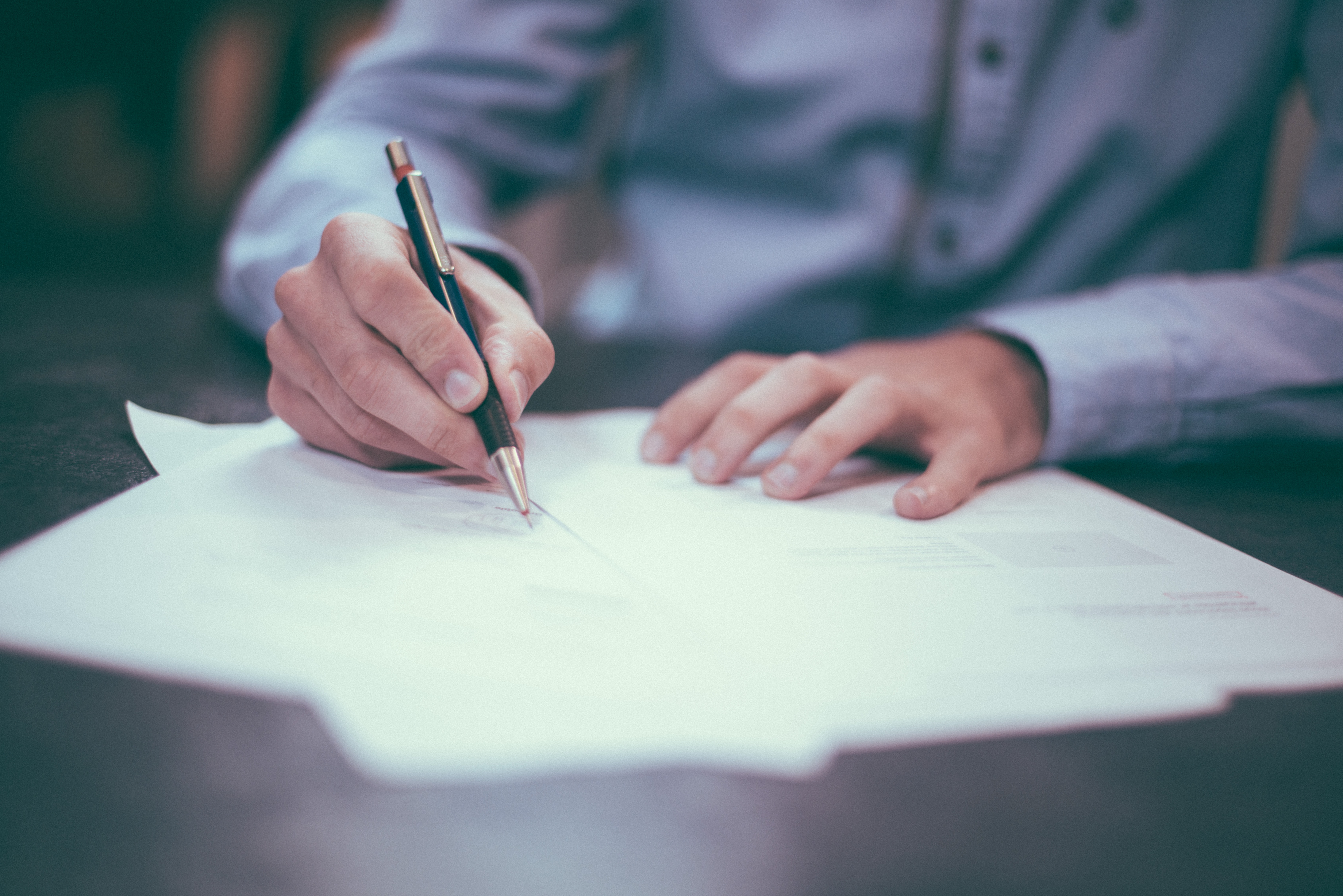 Man writing on paper with pen.